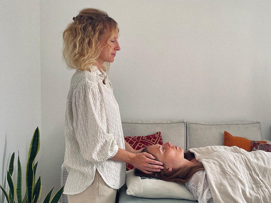 Séance de Reiki : Astrid impose les mains sur la tête d'une personne allongée